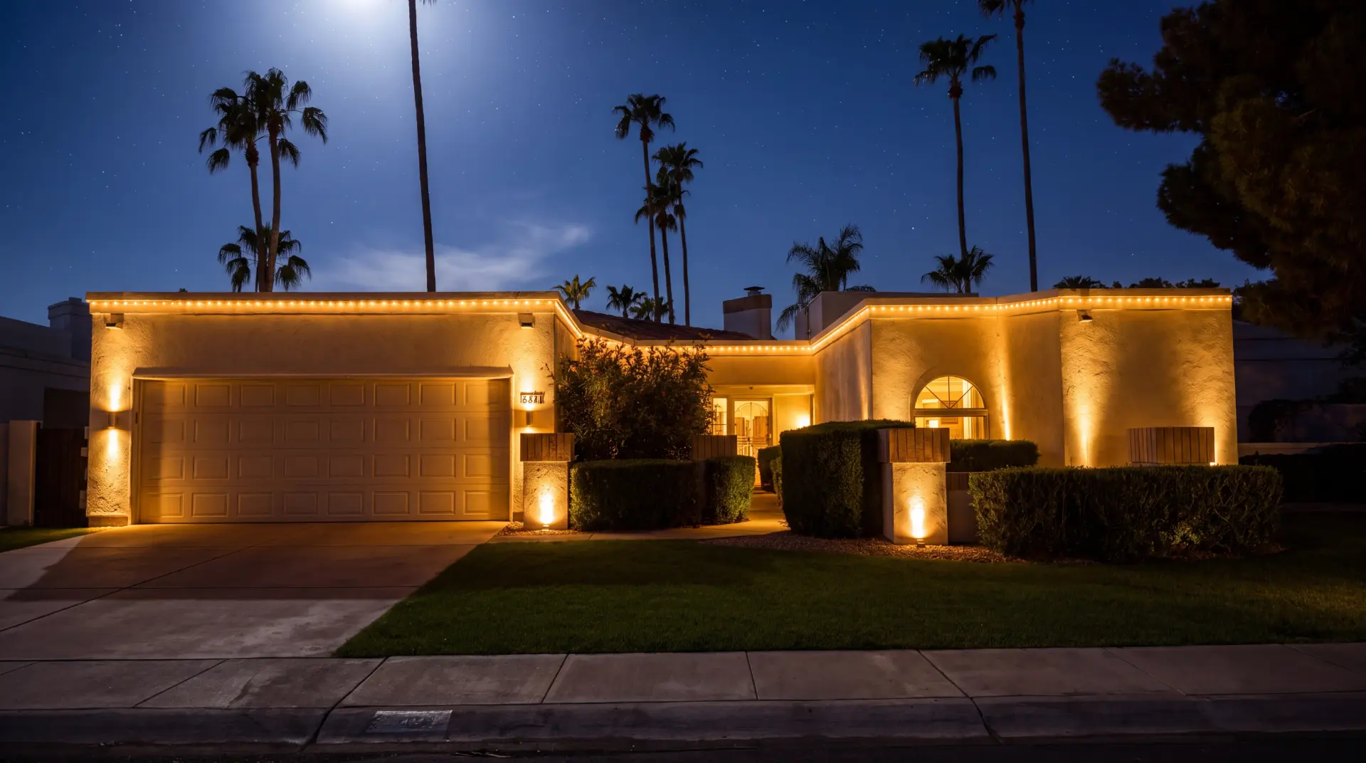 Same home glowing with warm roofline and uplighting after Awaken Lighting installation